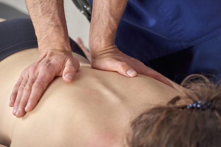 Young woman having chiropractic back adjustment. Physiotherapy, sports injury rehabilitation. Osteopathy, Alternative medicine, pain relief conceptの写真素材