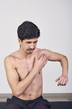 Young man with pain in the shoulder in a clinicの写真素材