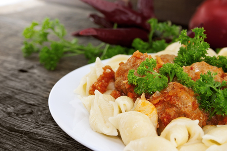 Pasta Conchiglie and meatballs with tomato sauce on rustic wooden background. Soft focus.の写真素材
