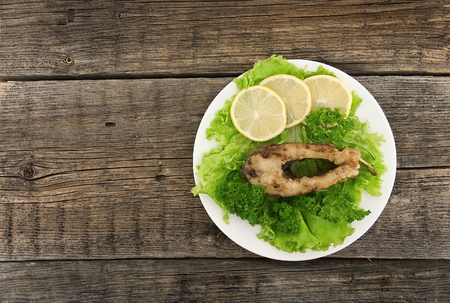 Roasted fish with fresh herbs and lemon on rustic wooden background. Top view.の写真素材