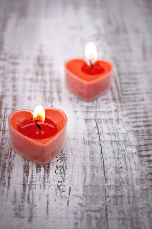 Red burning heart shaped candles on rustic white wooden table. Valentine's Day and Mother's Day background. Toned image. Soft focus.の写真素材