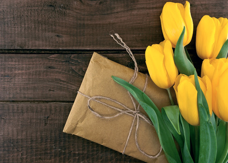 Bouquet of yellow tulips on dark rustic wooden background. Spring flowers. Spring background. Valentine's Day and Mother's Day background. Top view.の写真素材