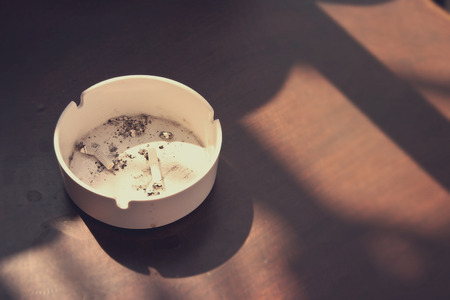 Ashtray stand on an old wooden table. Soft focus. Toned image.の写真素材