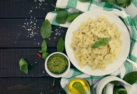 Farfalle pasta with pesto genovese (basil sauce) on rustic wooden table. Italian cuisine.  Flat lay. Top viewの写真素材