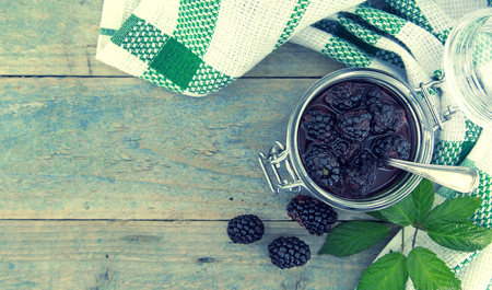 Homemade blackberries jam in a glass jar over rustic wooden table. Healthy food concept. Organic berries. Top view.の写真素材