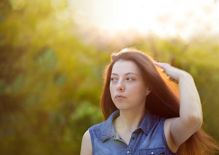 Attractive young woman with long brown hair enjoying hertime in the park with sunset in backgroundの写真素材