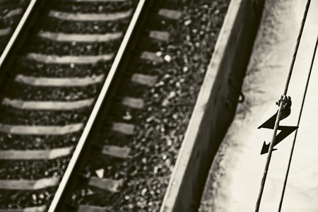 A warning danger electric sigh and the railway track in black and white. Selective focus.の写真素材