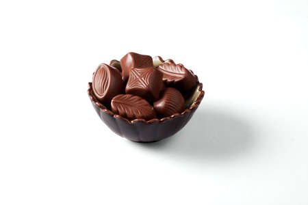 There are the chocolate candies in a nice bowl on a white background with shadowの写真素材