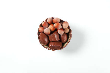 There are the chocolate sweets and nuts in a nice bowl on a white background.の写真素材