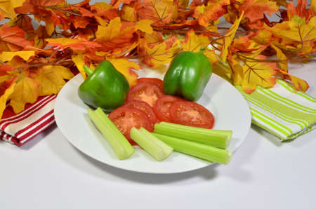 Vegetables on a white plate with seasonal foliageの写真素材