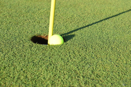 Concept of success and being a winner using a close-in shot of a golf ball in the hole on a golf course putting green. Seasonal summer sports activity.の写真素材