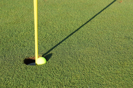 Concept of success and being a winner using a close-in shot of a golf ball in the hole on a golf course putting green. Seasonal summer sports activity.の写真素材