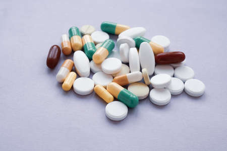 Colorful pills and capsules on a pink background, macroshot tablets, isolatedのeditorial素材