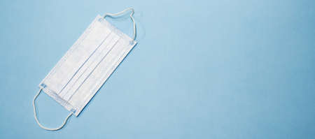 Disposable medical mask on blue background. Protective face mask from coronavirus. Surgical cotton mask Hygienic mask against the virus. Isolated antiviral mask. Web banner for site with empty spaceのeditorial素材
