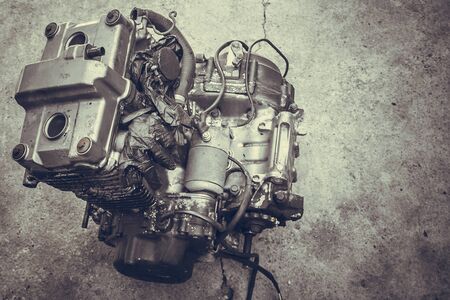 Old motorcycle engine isolated in a workshop, closeup. A biker metal motor lies on a cement...