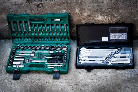 Professional mechanic tool kit in a box for repairing motorcycles and equipment. Closeup chrome steel tool on concrete in a garage. Collection of different wrenches in a drawer in a workshop.の写真素材