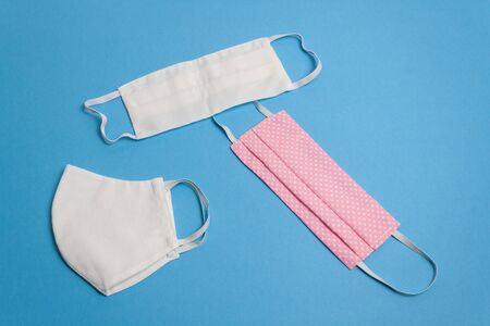 Three beautiful colored different reusable medical masks on blue isolated background. Hygienic, antimicrobial, antiviral tissue masks. Coronavirus protective equipment concept, top view.の写真素材