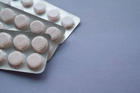 white round pills, three packs of pills, are located on the left side on a purple background, with...