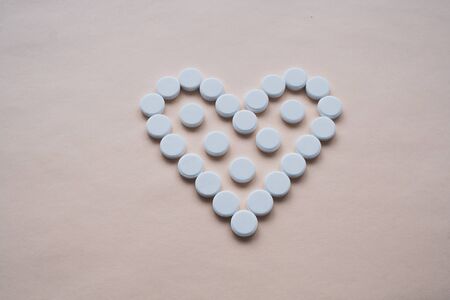 round white pills in the shape of a heart on a pink background, pills are located in the center, isolated, with a free area for textの写真素材