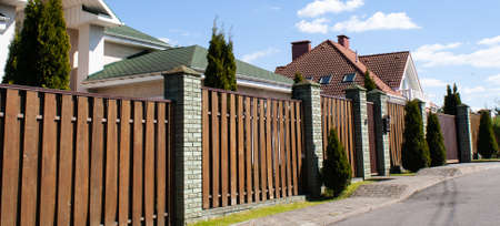 Wooden fence made of concrete pillars on an empty street in a cottage village Outdoor landscape....