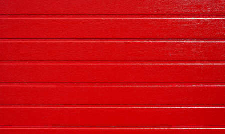 Red wooden background, horizontal striped texture. Folding garage door made of metal profile, red carbon. Red corrugated wallの写真素材
