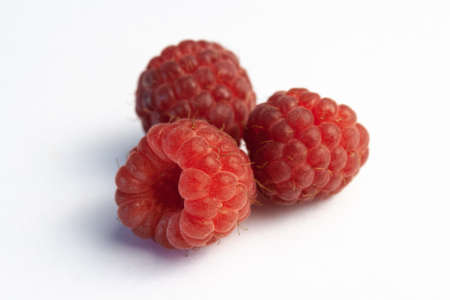 Three ripe raspberries isolated on a white background close-up. Fresh raspberries without sheets on the table. Macro shooting. Healthy and wholesome food conceptの写真素材