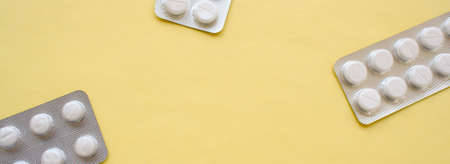 Packs of white pills, drugs lying on a yellow background. Prevention of coronavirus. Web banner on...