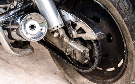 Rear wheel, exhaust pipe of sport motorcycle close up in garage. Back of motorcycle, chain, shock...