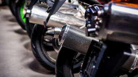 Many motorcycle parking in right way and orderly in one line. Exhaust pipes, rear wheels. Backs of modern sports bikes, side view, close-up. Road fast motorcycle in garage for repair. Moto tire.の写真素材