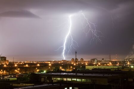 A powerful lightning strike hits the city at night. A strong lightning strike over a dark gray sky...