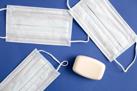 Close up of protective mask. Medical device for breathing and protection against coronavirus, pollution, virus and flu. Next to it is a piece of white hand soap Flat lay composition on blue backgroundの写真素材