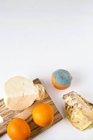 Spoiled, rotten cabbage and an orange with mold lie next to fresh oranges and cabbage. Inedible and edible vegetables and fruits. Isolated white background, flat lay, copy space.の写真素材