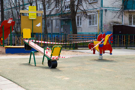 Moscow, Russia - April 26, 2020: Playground is closed due to coronavirus pandemic. A warning tape is block the swing. The children not play, they stay at home. Protection against disease covid-19のeditorial素材