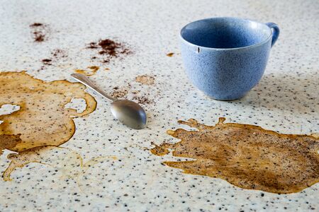 The empty blue cup is on the dirty table and there is a teaspoon. Cup marks, coffee stains on the surface. Close up composition.の写真素材