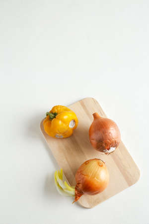 The whole spoiled, rotten onions and bell peppers lie on a wooden board on a white background. Mold on vegetables. Flat lay, close up with place for text composition.の写真素材