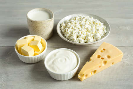Most common dairy products are butter, cheese, milk, sour cream, cottage cheese in white dish on a...