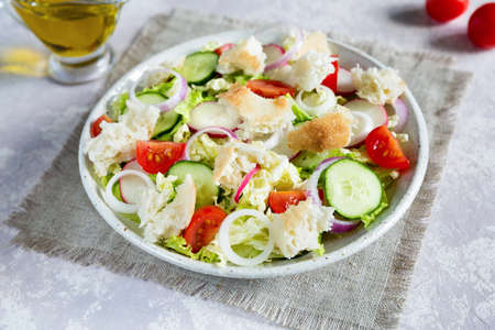 Lebanese salad fattoush. Healthy vegetarian food. Traditional lebanon salad with toasted pita bread and vegetables in the white plate on the canvas napkin with olive oil. Close upの写真素材