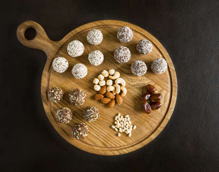 Raw vegetarian energy balls with cashews, hazelnuts, peanut butter and almond in the wooden board view from above on the dark background. Vegetarian, organic food.の写真素材