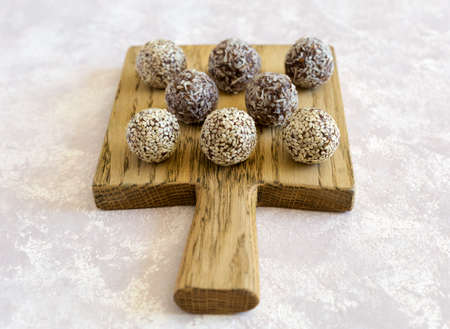 No bake sweets energy balls with hazelnuts, cashews, peanut butter and almond close up on the wooden board on the white background. Organic snack.の写真素材