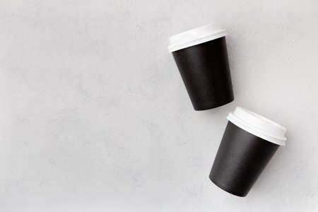 Disposable paper black cups with closed plastic lid for coffee to go, which is then recyclable. Take away drink. Mock up flat lay on gray background.の写真素材