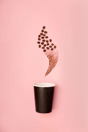 Disposable paper black cup mock up for coffee to go decorated with coffee beans flat lay on pink paper background.の写真素材