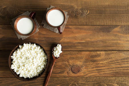 Dairy products cottage cheese and milk in wooden dishes cups and bowl top view on wooden background with place for textの写真素材
