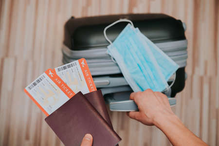 travel restriction due to the use of mandatory mask on airplane flights. Passport, plane ticket and suitcase ready for vacation.の写真素材