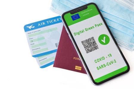 European Union digital green card with QR code on the mobile phone screen above the surgical mask, passport and airline ticket. Immunity from Covid-19. Travel without restrictionsの写真素材