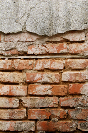 Old Wall of red bricks and damaged broken plaster, abstract background. Brick wall buildingの写真素材