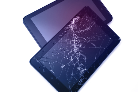 Photos of cracked display on a tablet and black cellphone isolated on white. Tablet with damaged screen.の写真素材