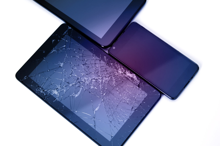 Photos of cracked display on a tablet and black cellphone isolated on white. Tablet with damaged screen.の写真素材