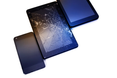 Photos of cracked display on a tablet and black cellphone isolated on white. Tablet with damaged screen.の写真素材