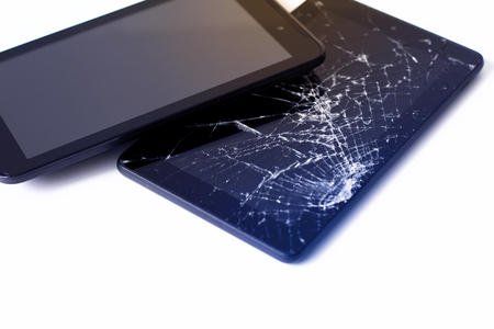 Photos of cracked display on a tablet and black cellphone isolated on white. Tablet with damaged screen.の写真素材