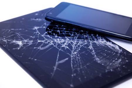 Photos of cracked display on a tablet and black cellphone isolated on white. Tablet with damaged screen.の写真素材